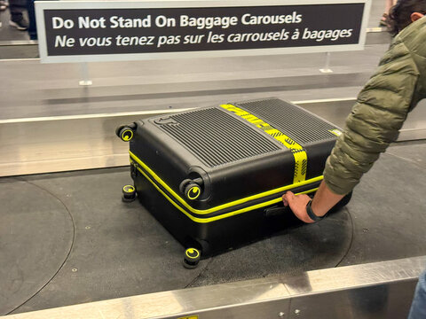 Black suitcase with yellow accents on baggage carousel at airport