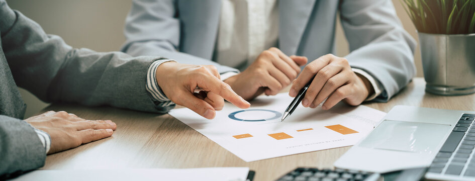 Financial advisors auditing data charts at office desk.
