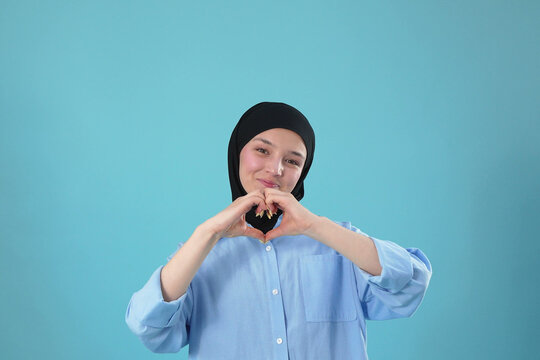 Young Muslim Woman in Hijab Making Heart Shape Gesture