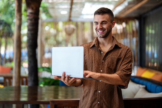 Happy digital nomad programmer working remotely on laptop in a stylish cafe