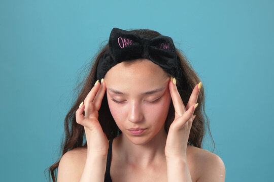 Young Woman with Headband Massaging Her Temples due to Headache or Stress
