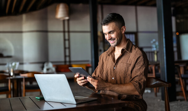 Creative male content creator writing a blog post in a bright, atmospheric cafe