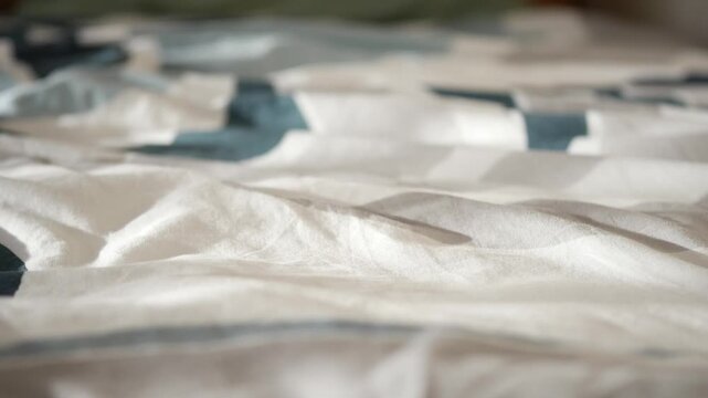 Soft wrinkles on a bed sheet create a simple pattern in a home setting