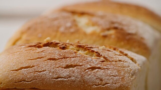 Slow motion close up of freshly baked bread with crumbs falling from crust on kitchen countertop in morning