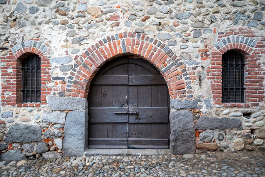 Italia, Ricetto di Candelo. Panorama di borgo medievale. Storia e cultura di Italia e d'Europa. Porta in legno isolata in primo piano.