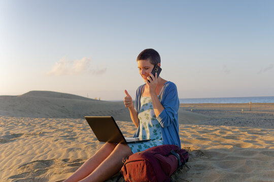 Woman giving thumbs up during phone conversation outdoors