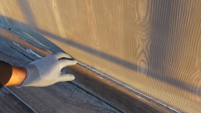 Worker Installing Baseboard Molding in a Room