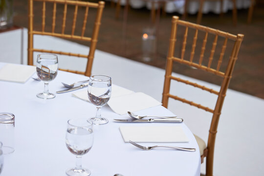 Elegant round banquet table setting with white tablecloth, crystal water glasses, and silver cutlery