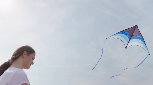 The girl looks up at the kite rear view close-up from below