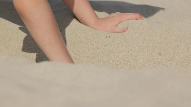 A boy is digging a hole in the sand close-up shot
