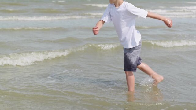 A boy is kicking the water by the sea