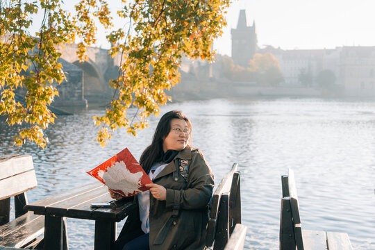 Korean tourist enjoys moment by triver in Prague, looking at map