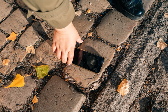 Holding a broken phone in hand while standing on stone pathway