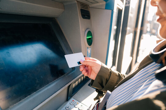 Person using an ATM in city, daylight to withdraw cash