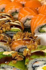 Salmon sushi rolls topped with avocado and fried onion pieces arranged on a plain white background © ir1ska