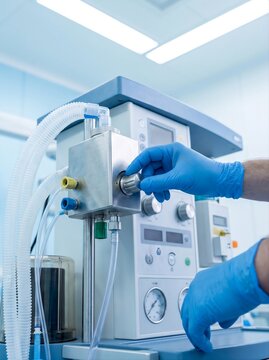 close-up of a respiratory care professional's gloved hands adjusting a medical air oxygen blender and inspecting the connected breathing circuit, precision flow control knobs, gas connectors