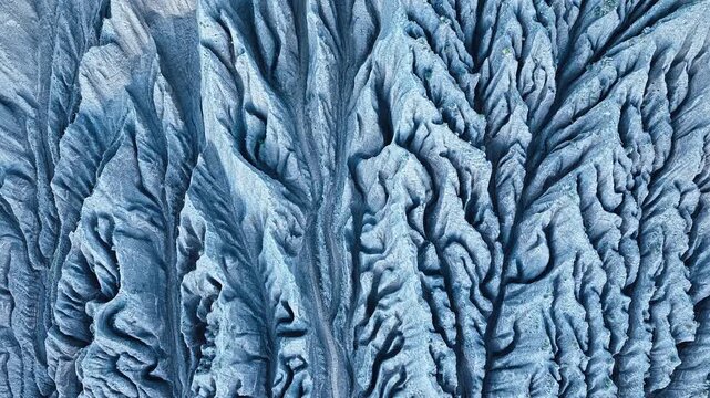 Intricate geological erosion patterns form dramatic ridges and ravines across a mountain slope in Xinjiang, China.