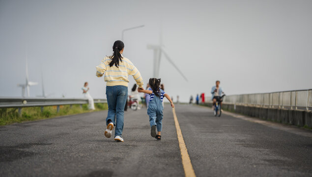 mother and preschool child girl holding hand and running on a road on mountain in morning