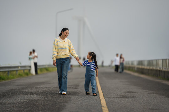 mother and preschool child girl holding hand and walking on a road on mountain in morning