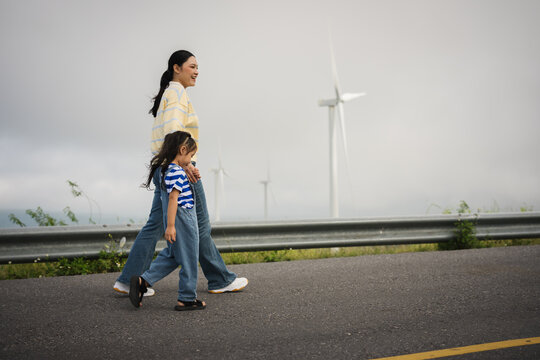 mother and preschool child girl holding hand and walking on a road on mountain in morning