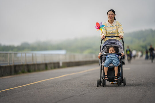 mother walking with child girl sleeping in stroller along the road