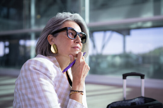Businesswoman thinking and waiting with luggage
