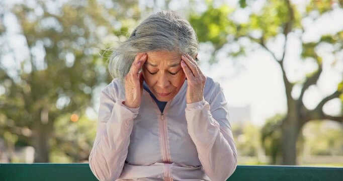 Senior, woman and headache with stress on park bench for mental health, strain or pressure. Elderly, female person or migraine with pain or vertigo for dizziness, fatigue or memory loss in nature