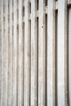 Abstract pattern of vertical concrete slats in soft neutral tones.