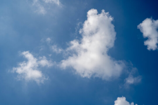 Fluffy white clouds drifting in a bright blue sky.