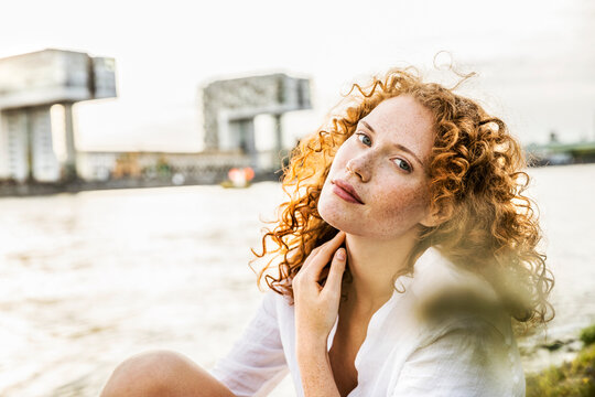 Germany, Cologne, portrait of freckled young woman with curly red hair