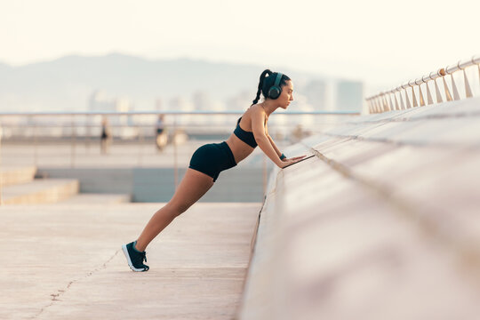 Fit woman doing incline push up workout outdoors