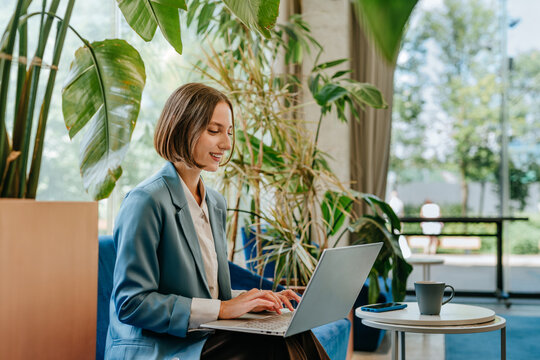 Smiling businesswoman using laptop in a modern green office