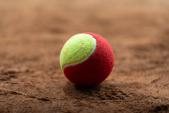 Red and Yellow Tennis Ball on Clay Court Close-Up