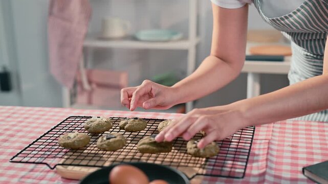 Woman arranging homemade matcha cookies on cooling rack
