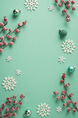 Naklejka premium Merry Christmas teal holiday vertical flat lay with snowflake ornaments, frosted berries and Happy New Year accents