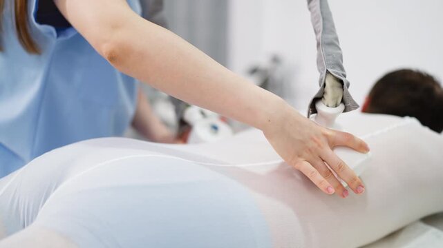 Beauty specialist performing professional body treatment on male client using modern aesthetic equipment. Concept of LPG massage, non invasive body contouring, advanced beauty technology, men wellness