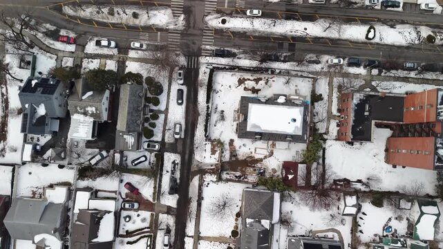 An overhead Queens street grid creates rectangular blocks of closely packed roofs with patches of winter snow.