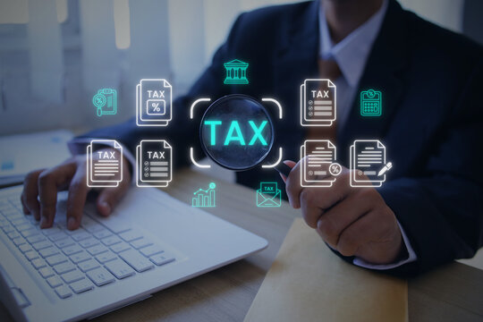 Man in Suit Holding Magnifying Glass on Virtual Tax Hologram Icon while Using Laptop