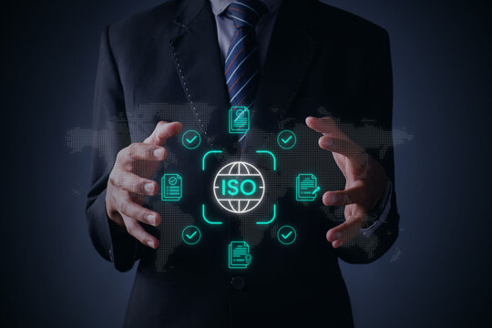 Businessman Presenting ISO Quality Control Assurance Interface Hologram Against Grey Background