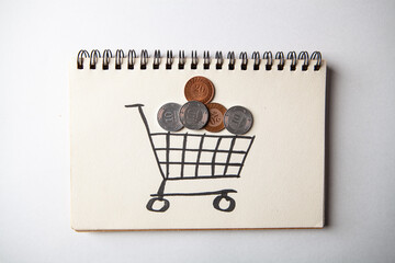Shopping cart and coins on paper background. © Artvibe