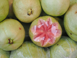 Pink guavas feature a vibrant reddish-pink flesh  they are carved into star shapes to stand out among the other fruits on the stall. © saksuvan