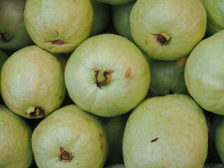 Pink guavas feature a vibrant reddish-pink flesh  they are carved into star shapes to stand out among the other fruits on the stall. © saksuvan