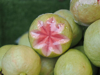 Pink guavas feature a vibrant reddish-pink flesh  they are carved into star shapes to stand out among the other fruits on the stall. © saksuvan