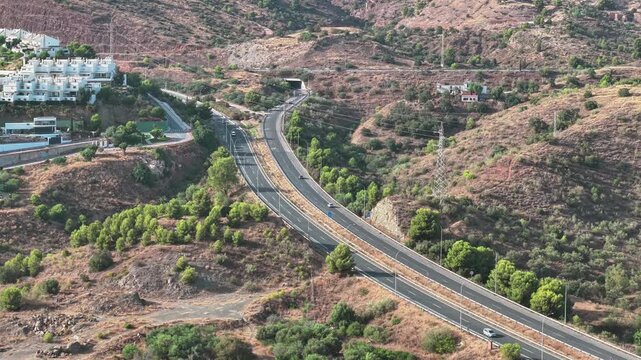 Aerial view of cars driving along the A7 highway near Malaga, Spain with a tunnel cutting through the hillside