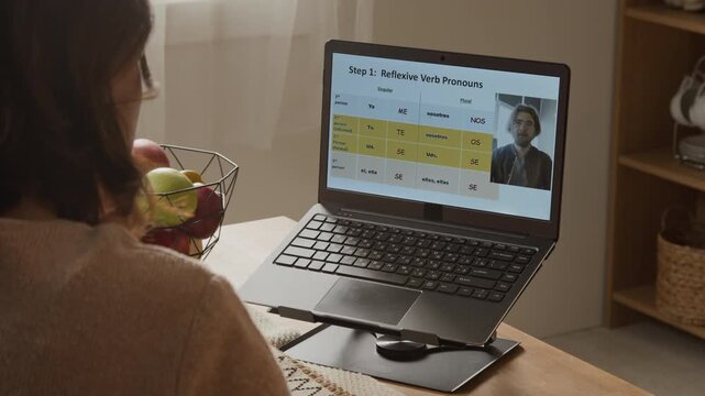 Unrecognizable woman attending online language lesson on laptop via video call. Footage perfect for advertising e-learning platforms, remote education services, and tutoring apps