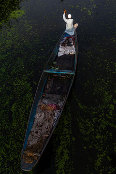 Aerial view of a boatman rowing a long wooden shikara on dark water, Jammu and Kashmir, Srinagar, India