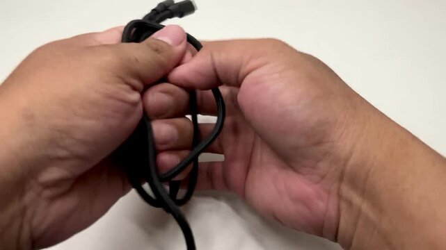 A persob coiling and organizing a multi conector power charging cable.