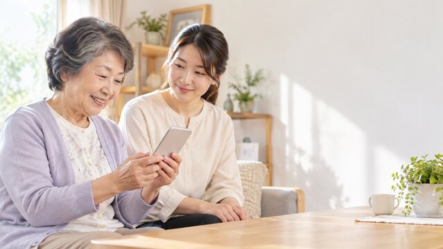 携帯端末の操作を相談する高齢女性と成人女性