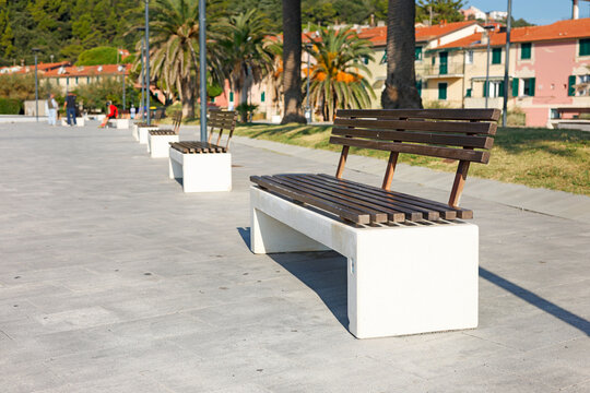 Empty wooden bench sunny seaside promenade. Vacation relaxation wellness calm mood. Travel destination urban living hospitality guide.