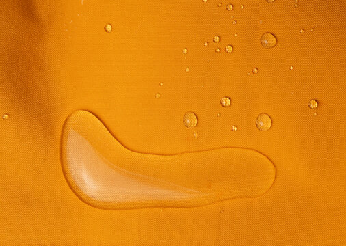 Macro shot of raindrops on vibrant orange hydrophobic fabric